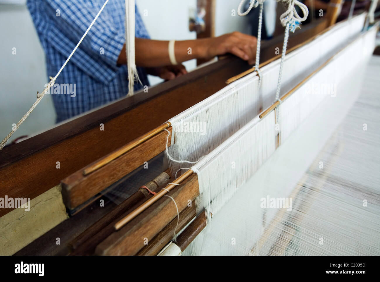 A man works a hand loom to produce silk material at Pak Thong Chai, near Phimai, Nakhon Ratchasima province, THAILAND. Stock Photo