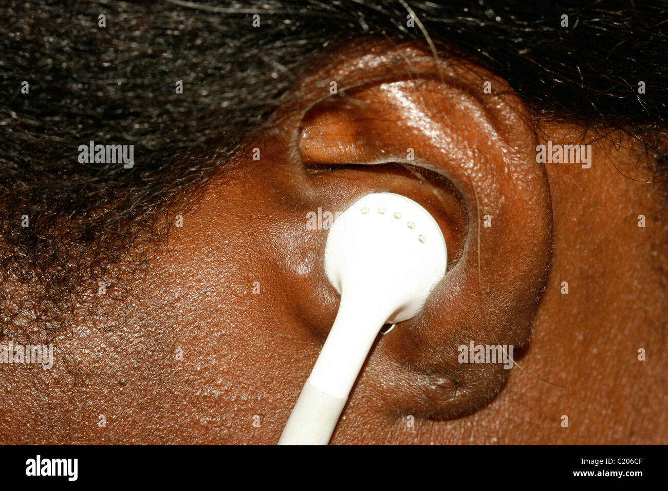 A young African woman with an earpiece listening to an MP3 player Stock Photo