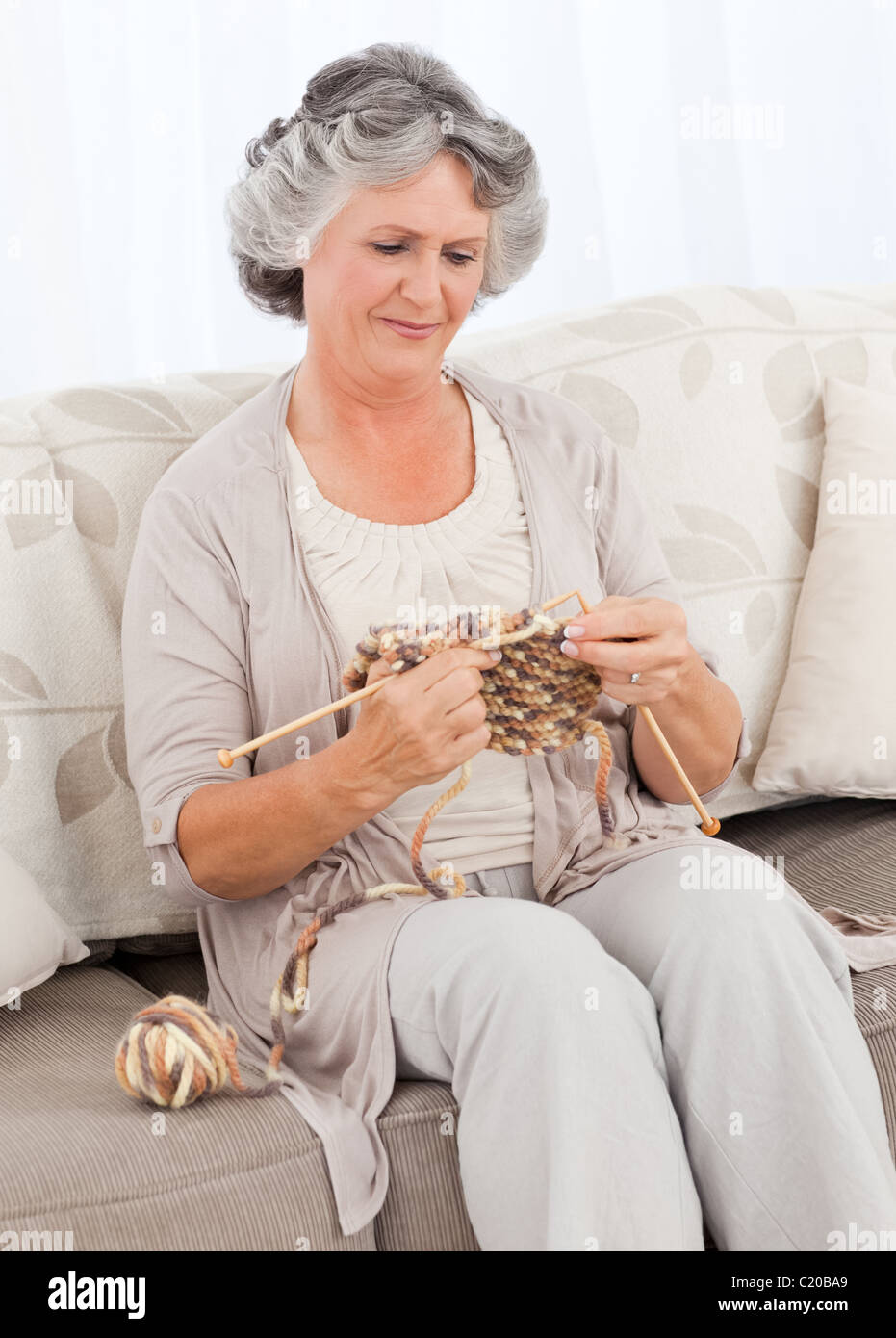 Senior woman knitting on her sofa Stock Photo - Alamy
