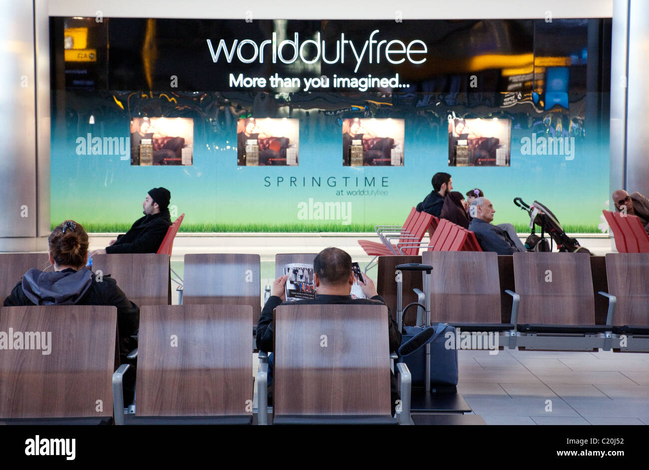Passengers in the departure lounge against the backdrop of the World Duty Free store, Terminal 5, Heathrow airport, London UK Stock Photo