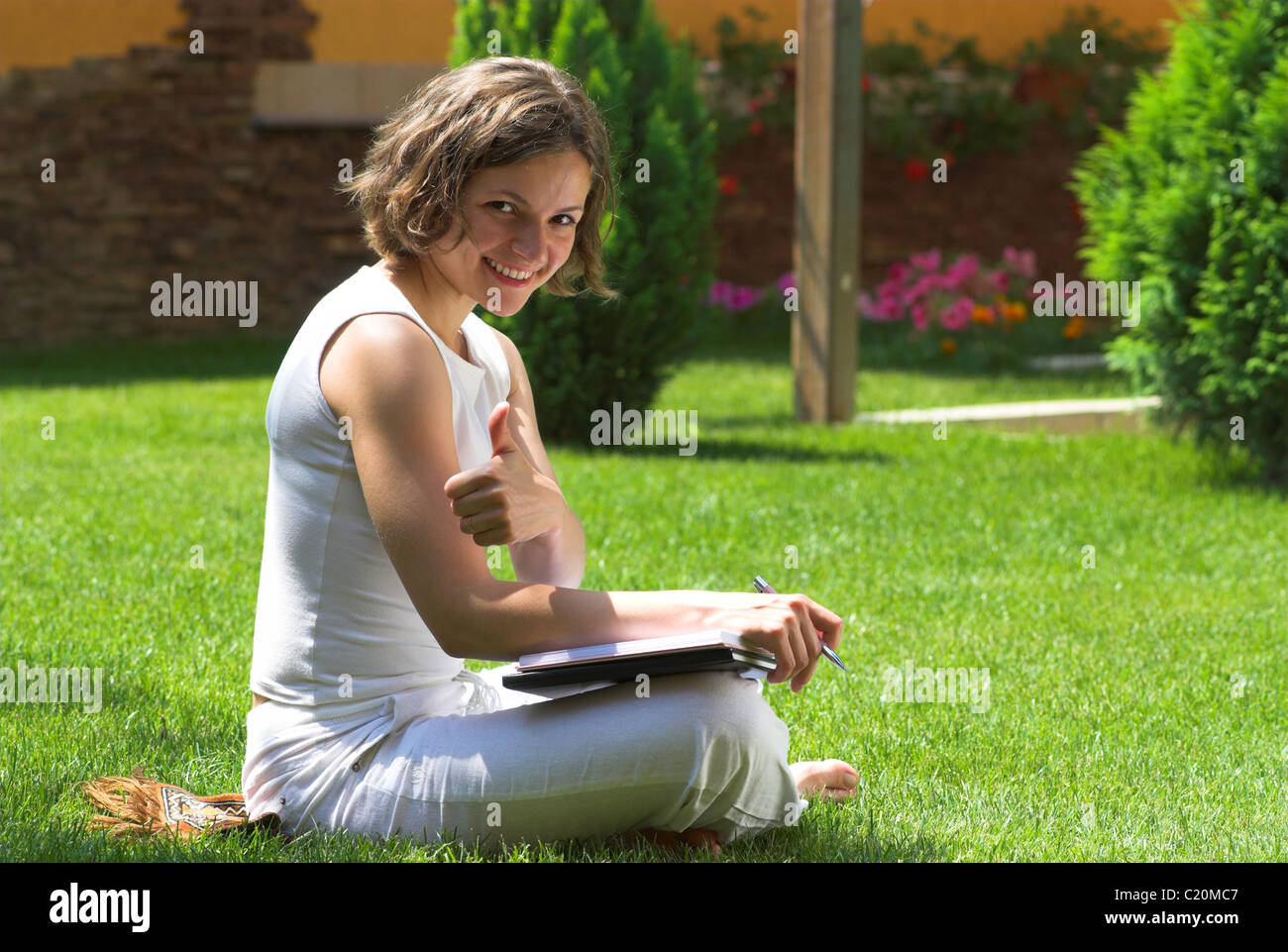 Young student with thumb up on campus lawn Stock Photo - Alamy