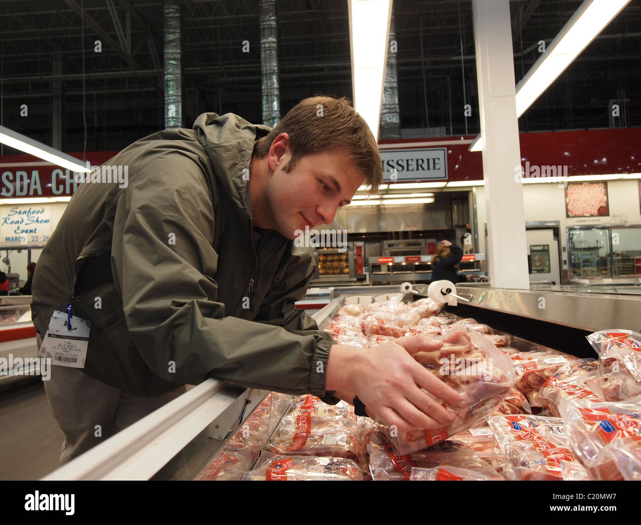 A man selecting bulk package of chicken at Costco Wholesale, a USA big box chain store, March 24, 2011, Katharine Andriotis Stock Photo