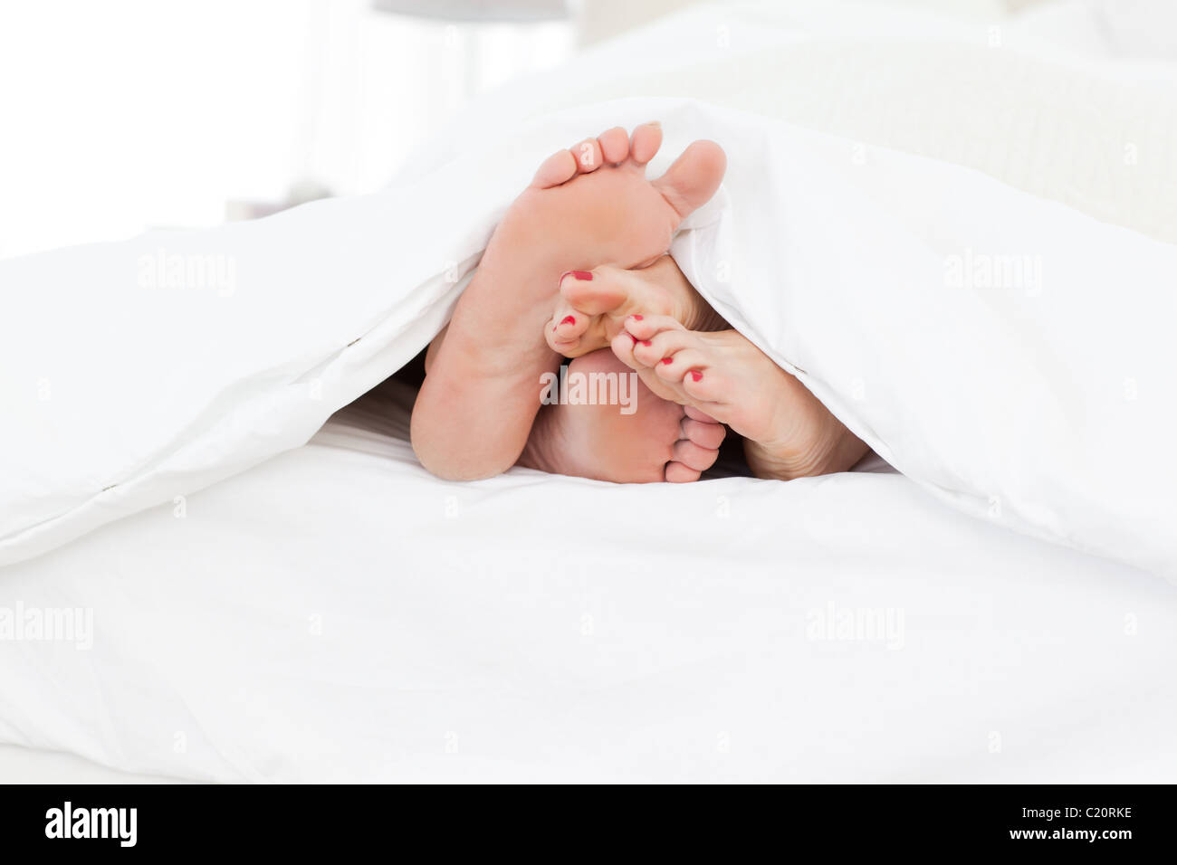 Couple showing their feet while lying on a bed Stock Photo
