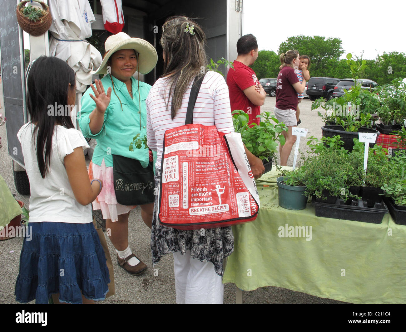Woman buying plants from a friendly Asian vendor at a farmers market in Austin, Texas Stock Photo