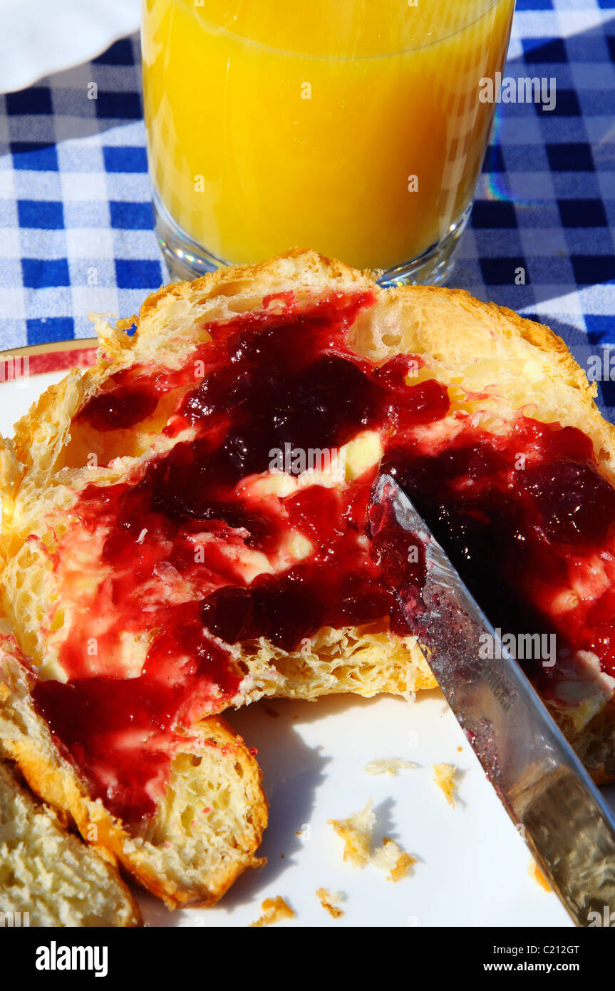 Spreading raspberry jam on a croissant, Mijas Costa, Costa del Sol ...