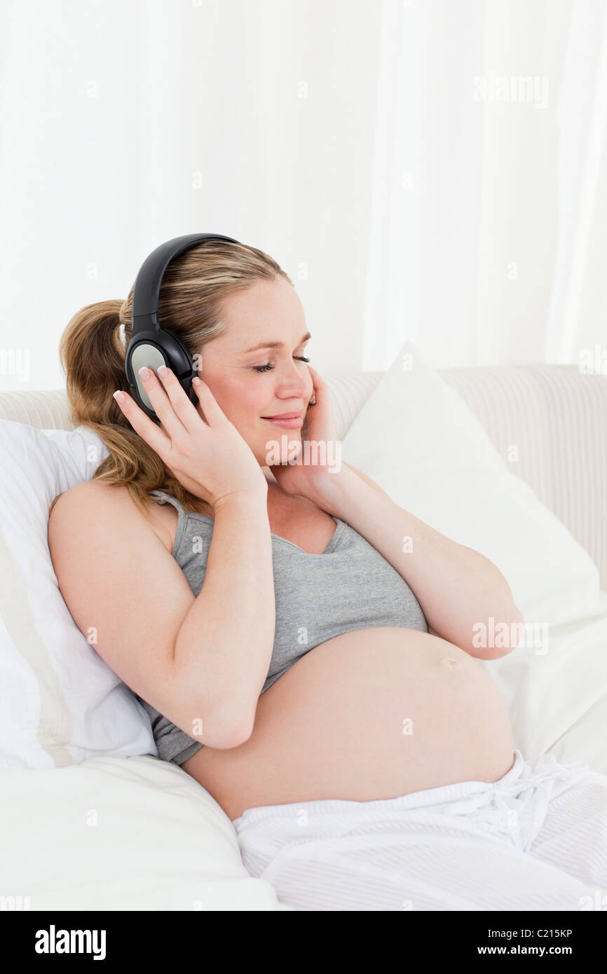 Lovely pregnant woman listening to music on her bed Stock Photo - Alamy