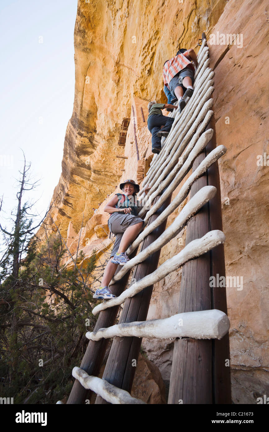 A woman poses for a picture on a ladder leading up to Balcony House cliff dwelling in Mesa Verde National Park, Colorado, USA. Stock Photo