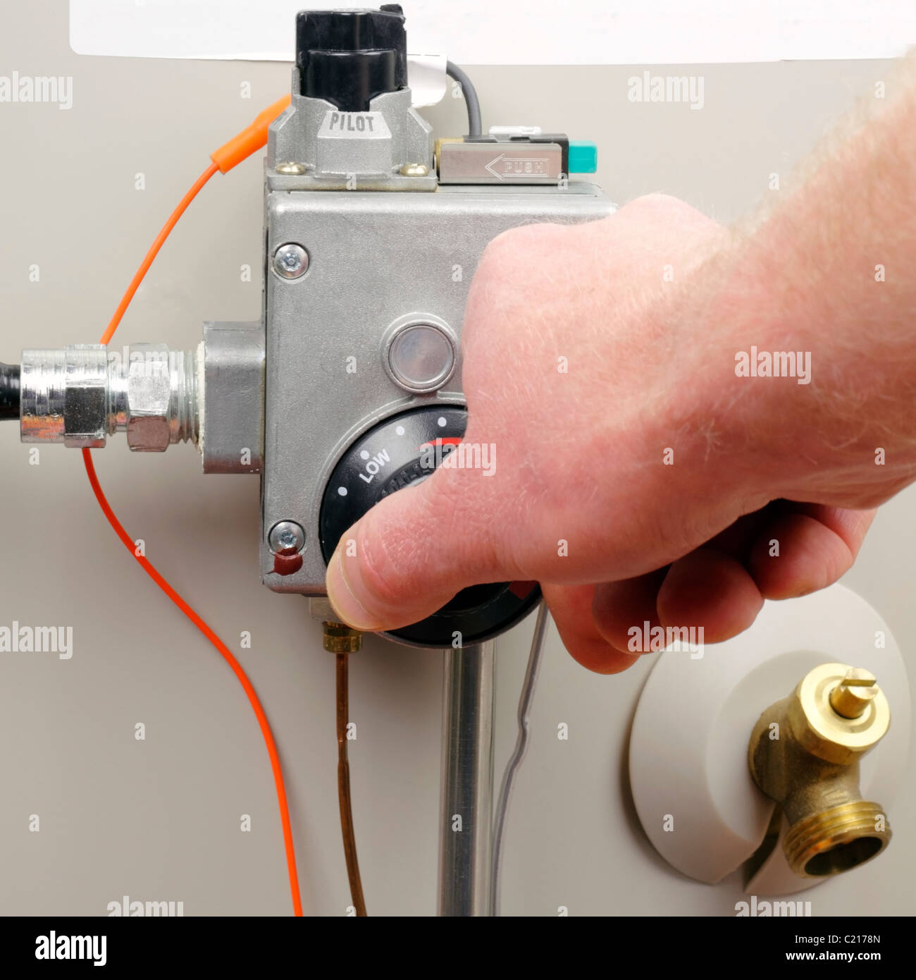 Hot water heater gas boiler tank thermostat temperature adjusted for household. Hand of a man turning down household gas water heater temperature. Stock Photo
