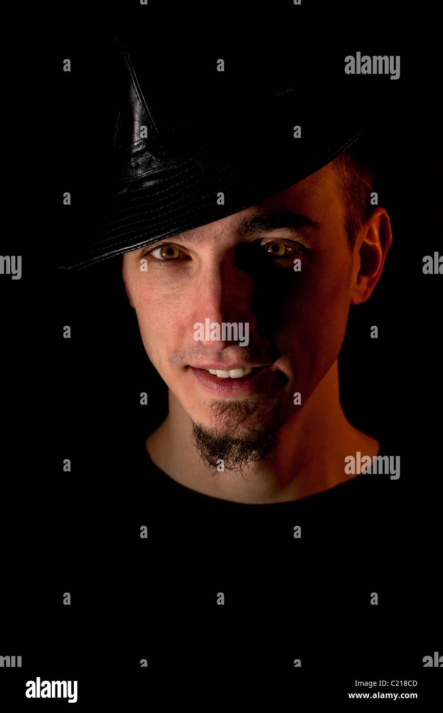 Studio portrait of smiling handsome man in hat over black background ...