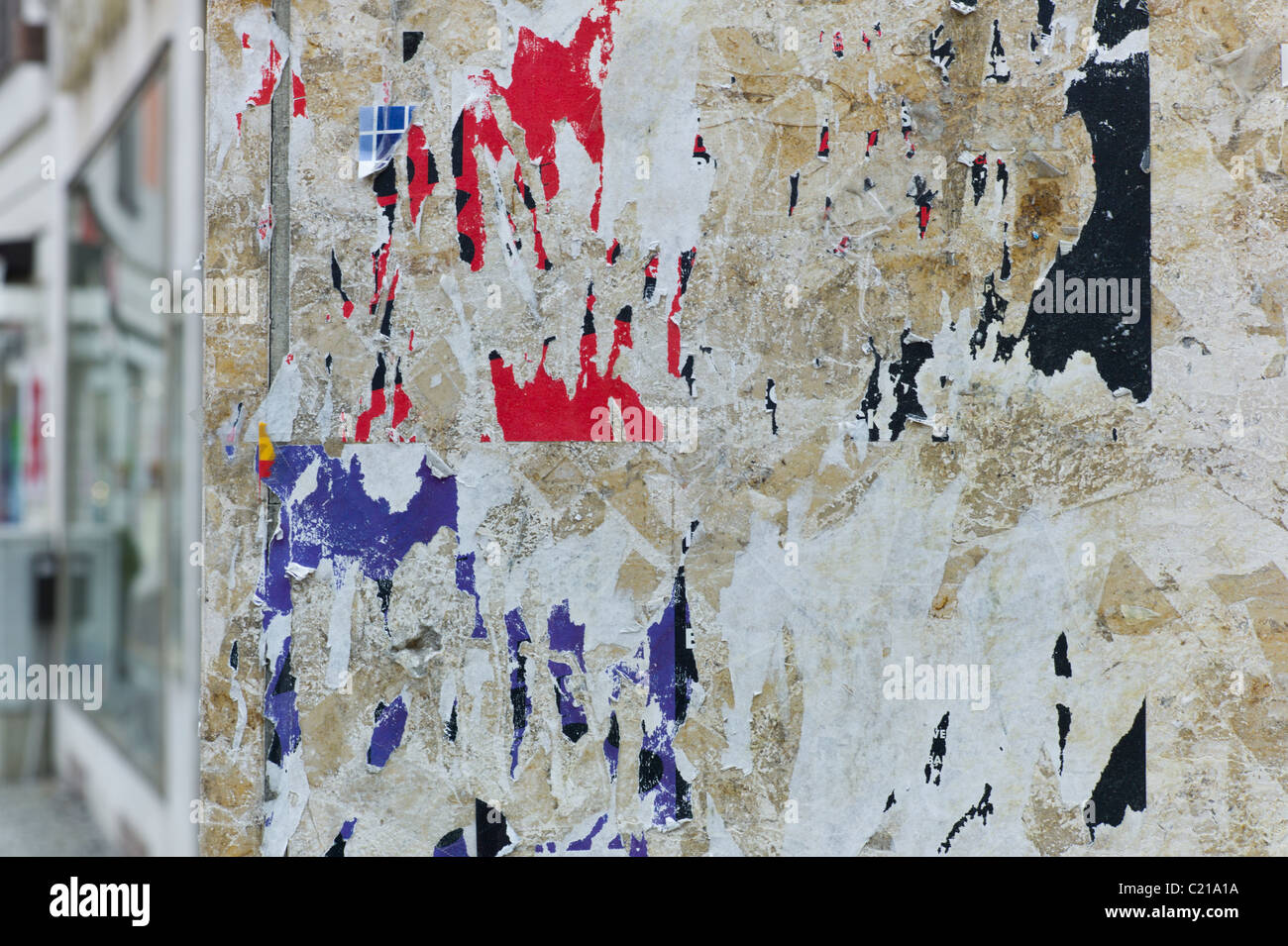 Wall of a house with colorful remains of posters and stickers on it, Munich Stock Photo