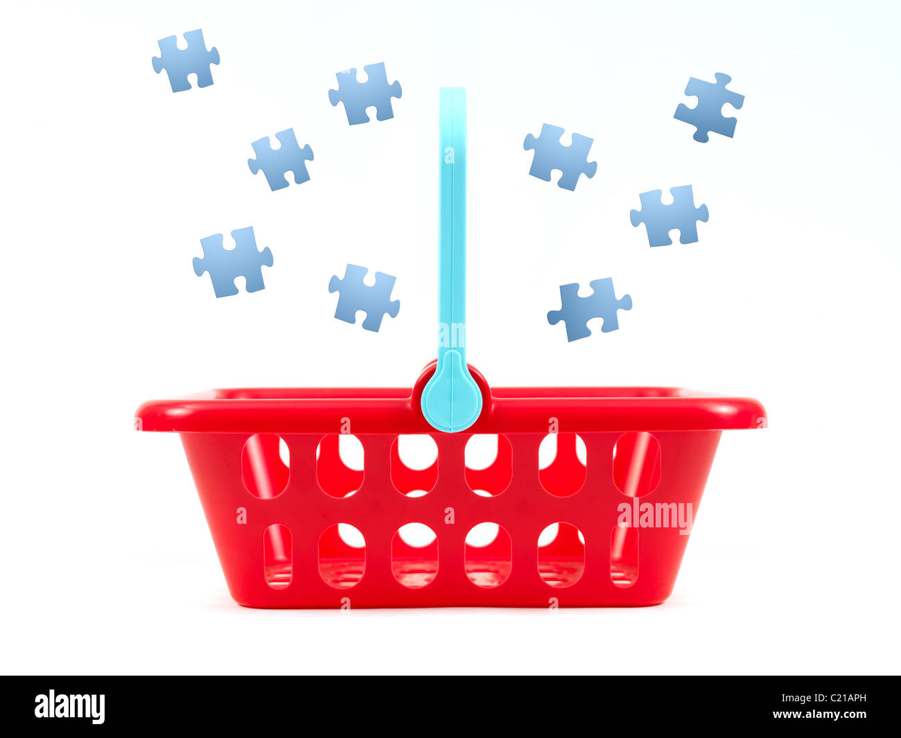 Jigsaw pieces falling into a shopping basket isolated against a white background Stock Photo
