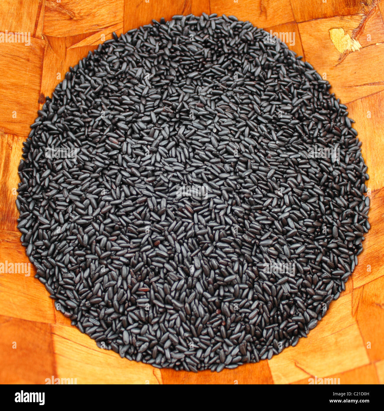 Organic dry black purple rice shaped into a circle in a wood bowl, square photo. Black indigo gourmet organic rice in the center of a wood grain bowl Stock Photo