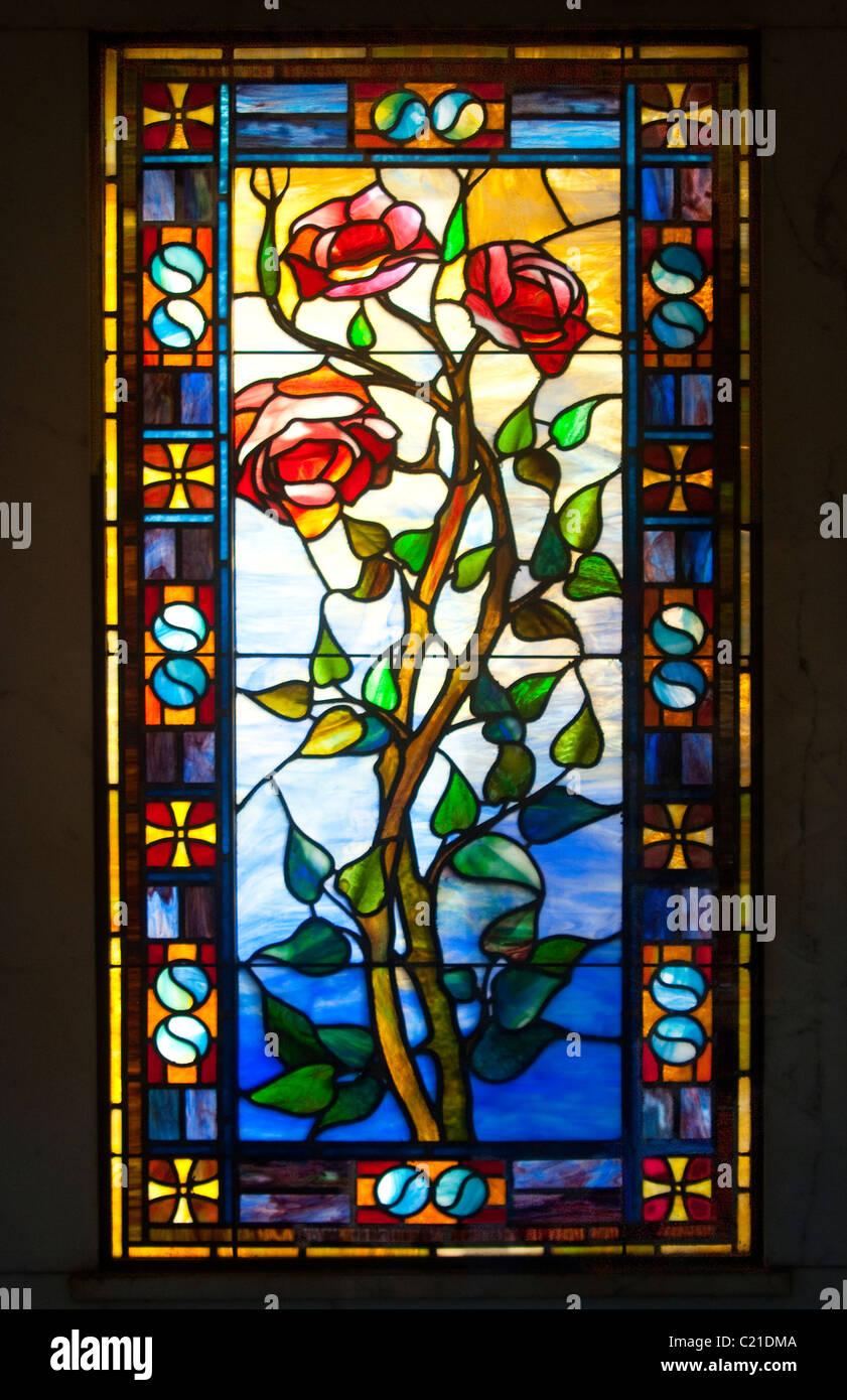 Antique stained glass window of roses on the vine, surrounded by ying/yang symbols. Stock Photo