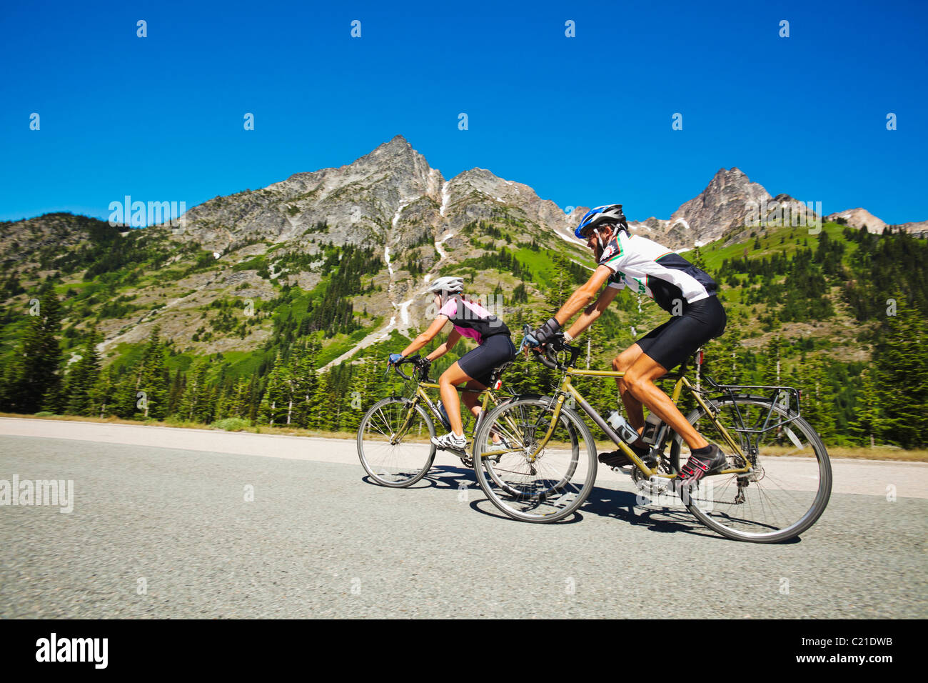 A young man and woman riding their bicycles on Highway 20 in the North Cascades of Washington State. Stock Photo