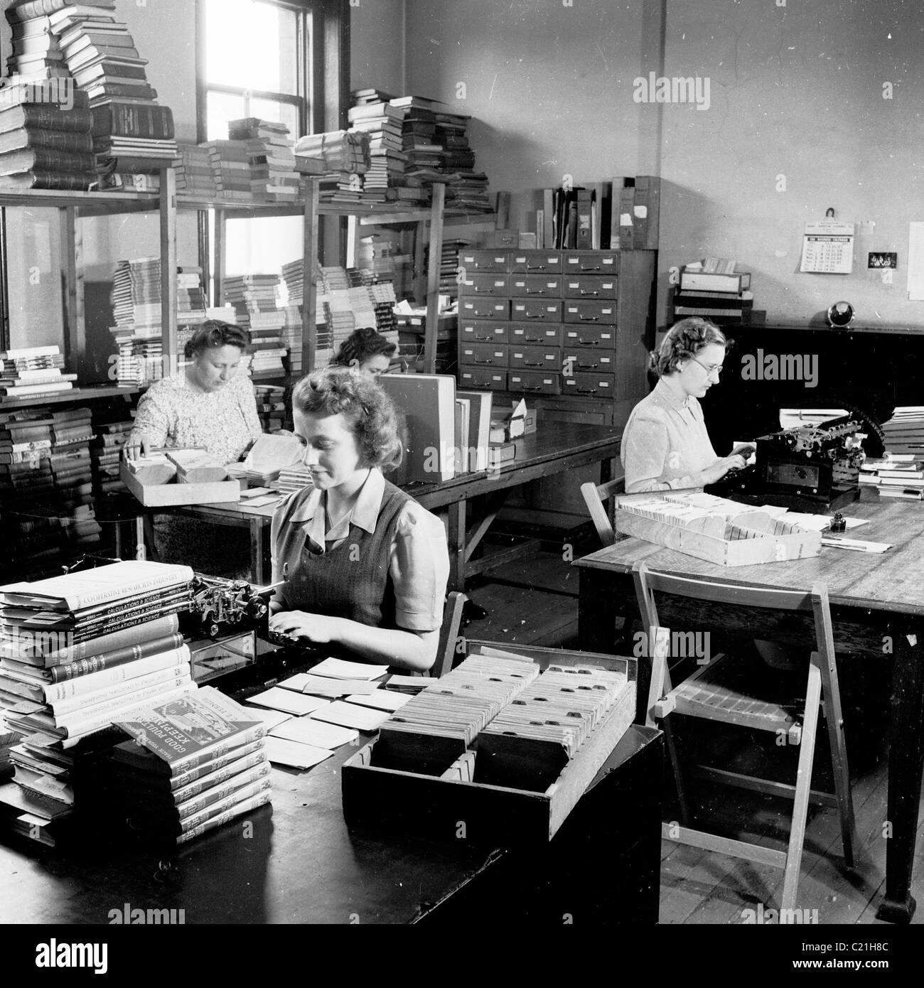 1950s, England. Secretaries working at typewriters in an office of a