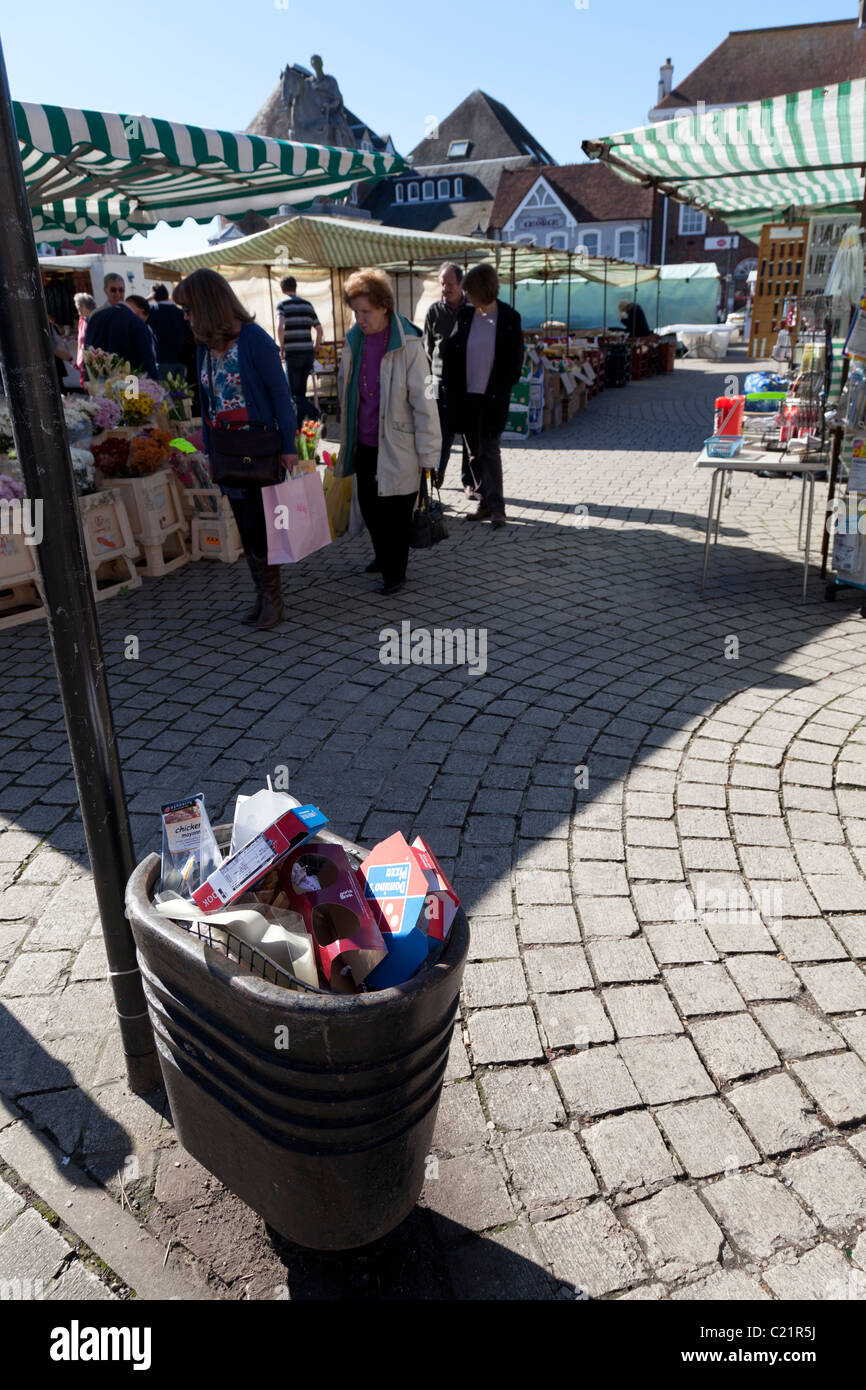 full rubbish bin in front of market stalls Stock Photo