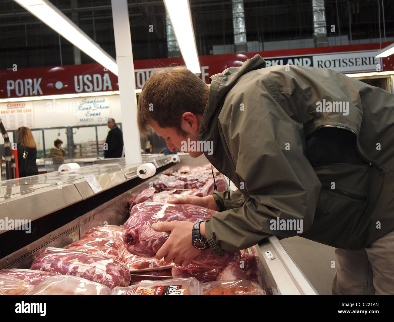 A man selecting bulk package of meat at Costco Wholesale, a USA big box chain store, March 24, 2011, Katharine Andriotis Stock Photo