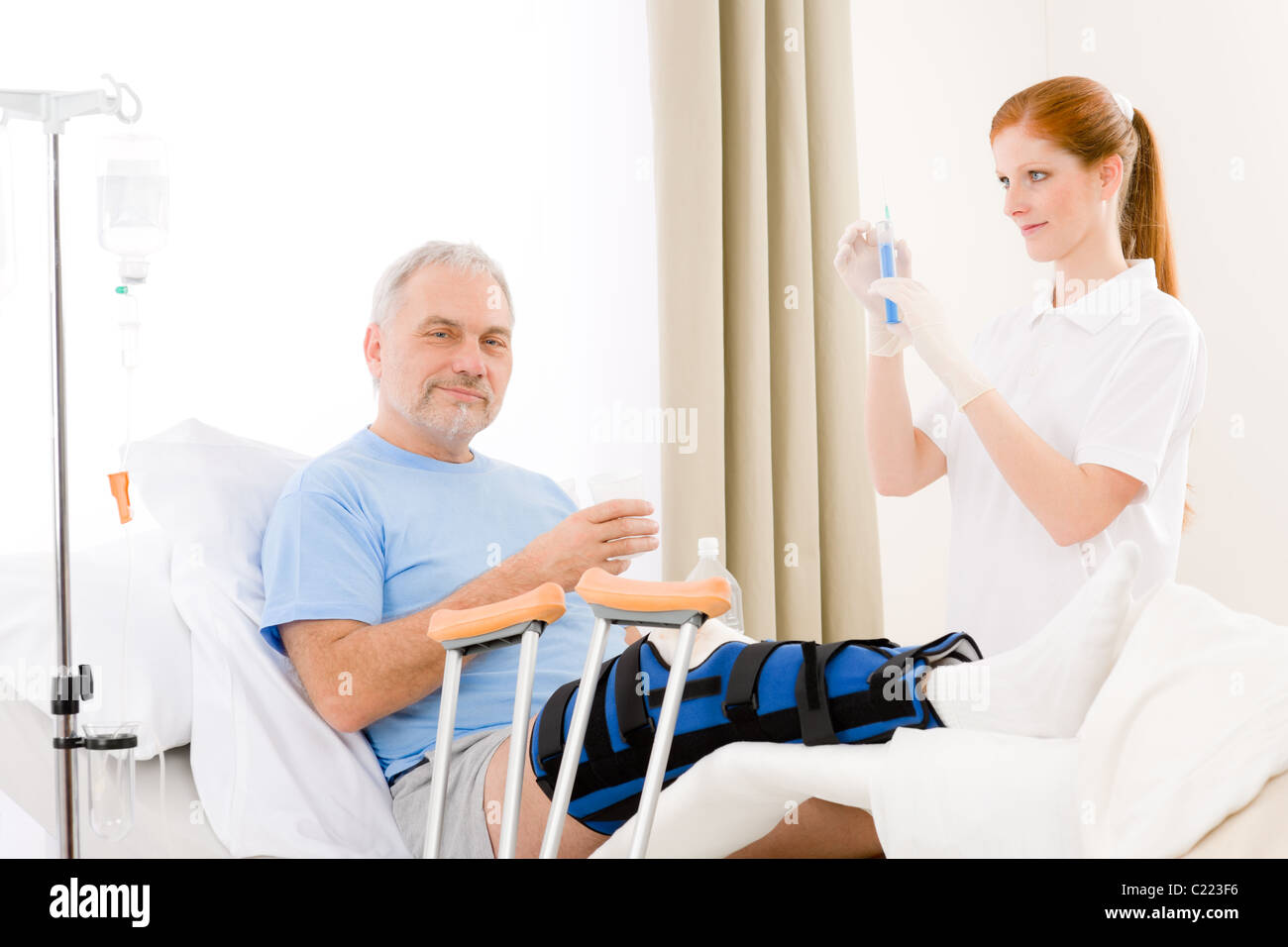 Hospital - female nurse give injection patient with broken leg Stock Photo