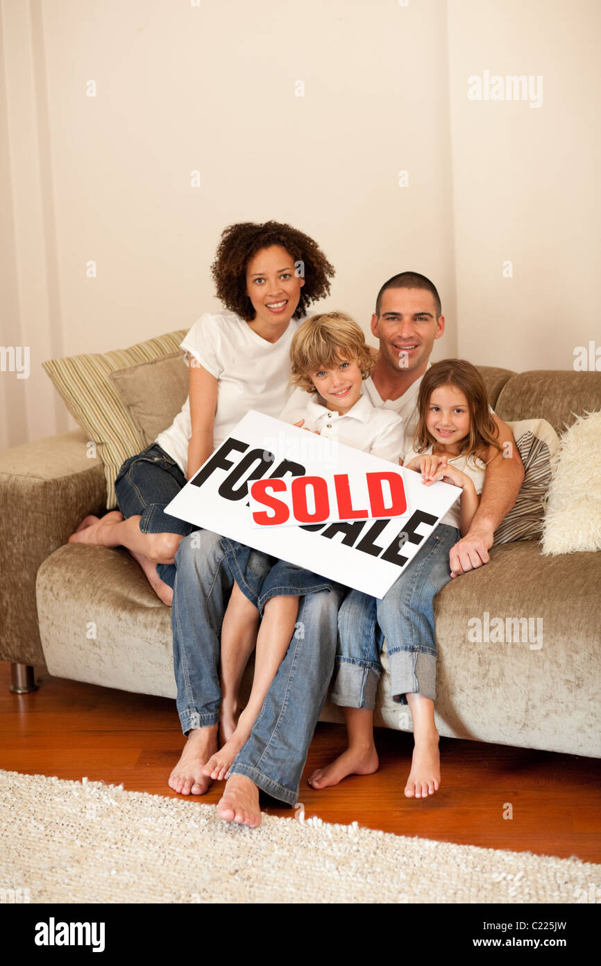Young family sitting on the sofa with a plakat Stock Photo