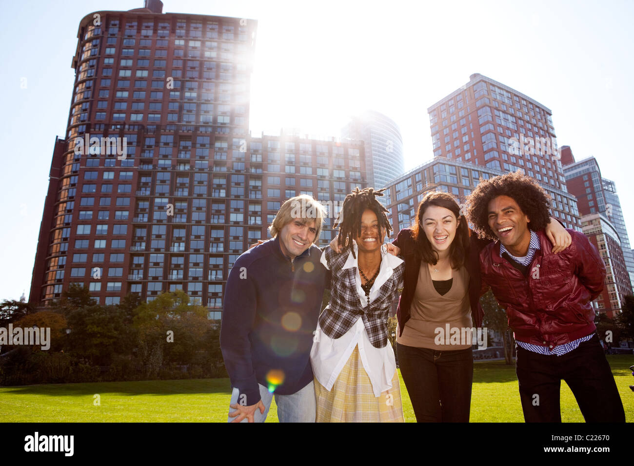 A group of young adults in a city park - shot into the sun with solar flare Stock Photo
