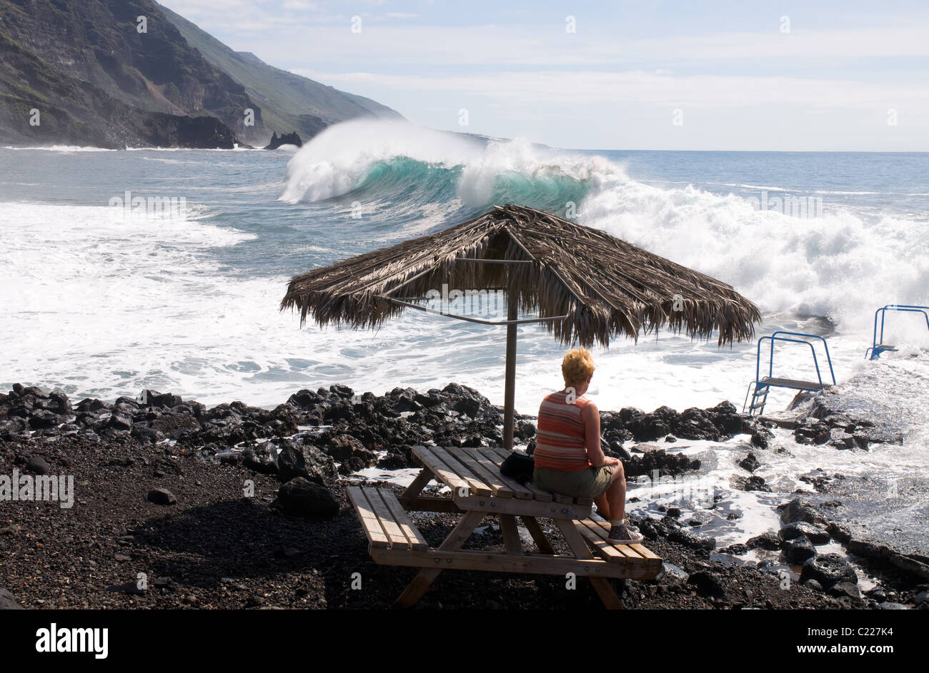Woman watching big waves crashing in on a beach in La Palma Canary Islands Stock Photo