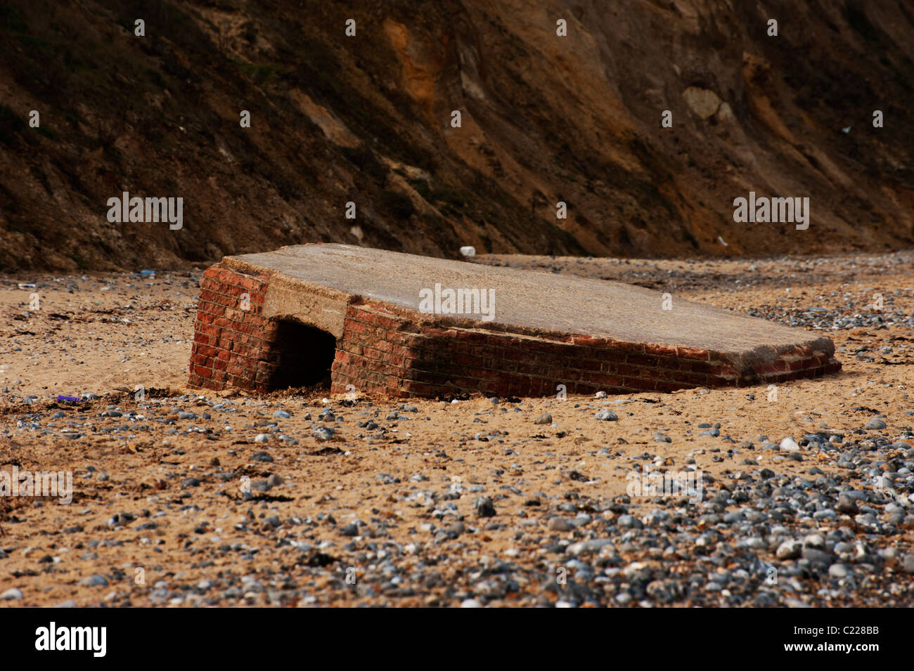 On the beach between Cromer and East Runton a WWII pillbox defense sinks into the sand. Stock Photo