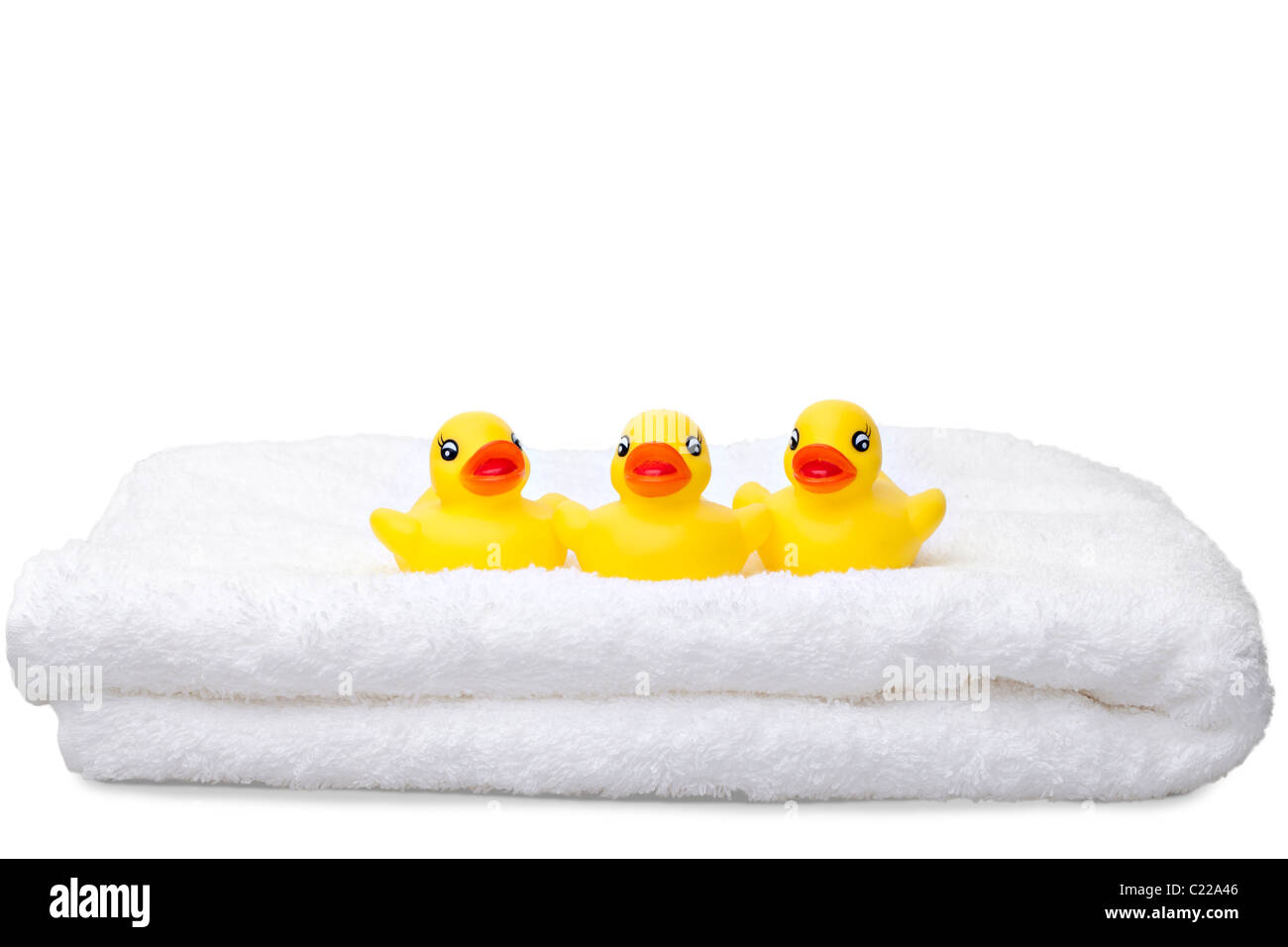 Three yellow rubber ducks in a row on a fluffy white towel isolated