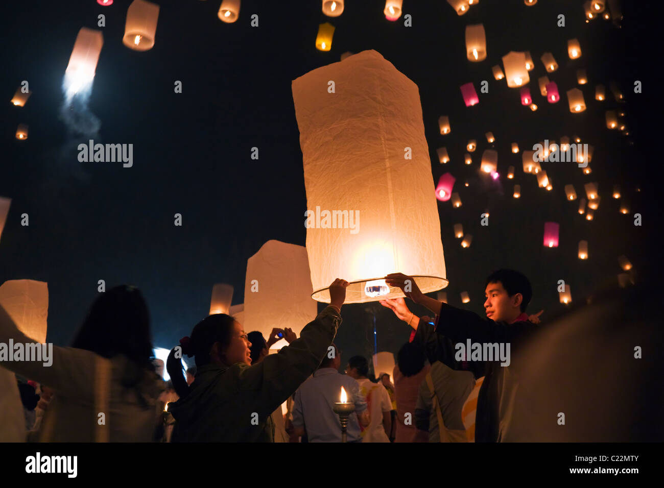 Revelers launch khom loi (sky lanterns) into the night sky during the Yi Peng festival.  San Sai, Chiang Mai, Thailand. Stock Photo