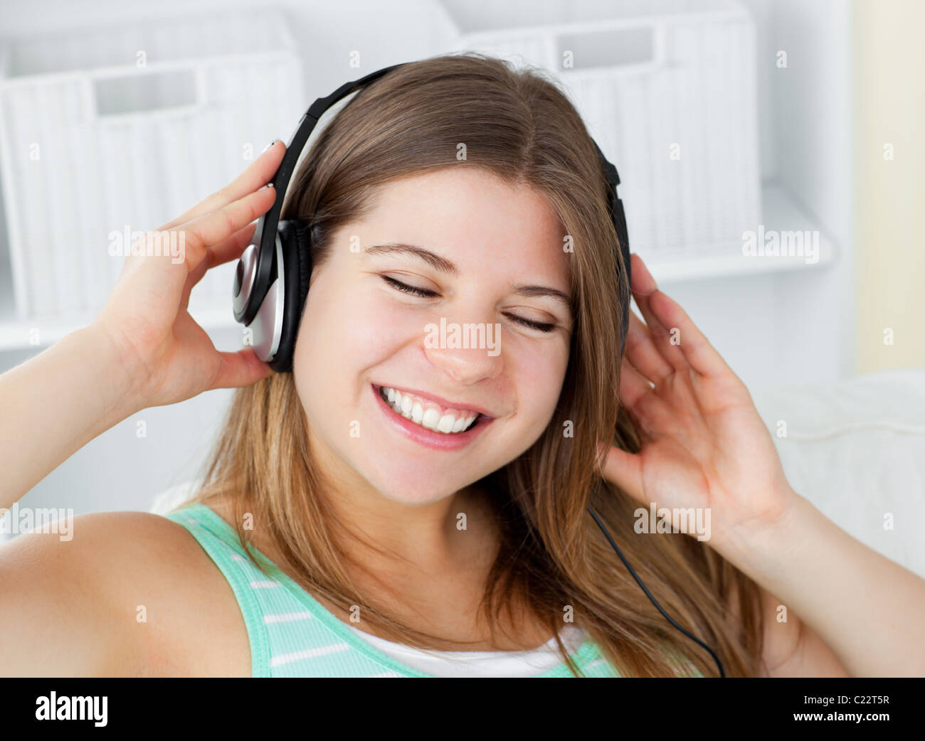 Cheerful young woman listening to music with headphones on a sofa Stock ...