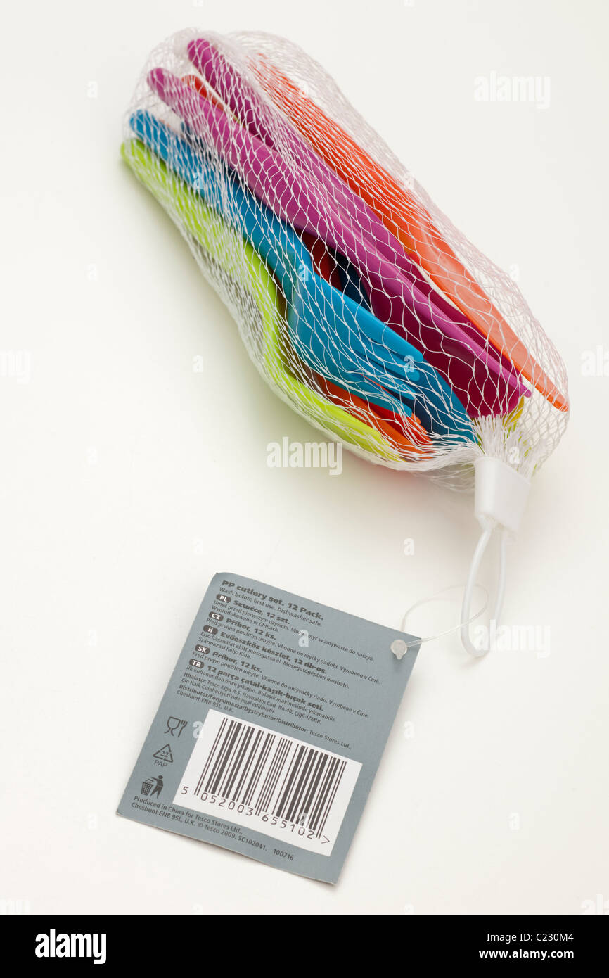 Set of brightly coloured plastic picnic knives forks and spoons in a white mesh bag with bar coded label Stock Photo