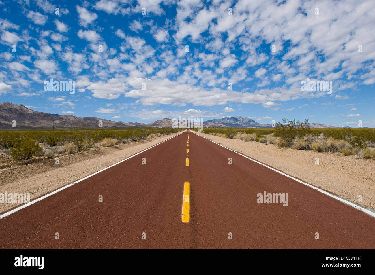View from the middle of a straight road running through deserted land Stock Photo