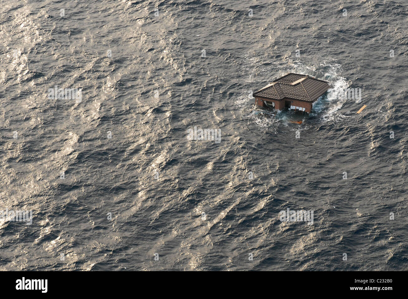 Aerial photo taken March 13 2011 of a house floating at sea near Sendai, Japan, in the aftermath of the earthquake + tsunami. Stock Photo
