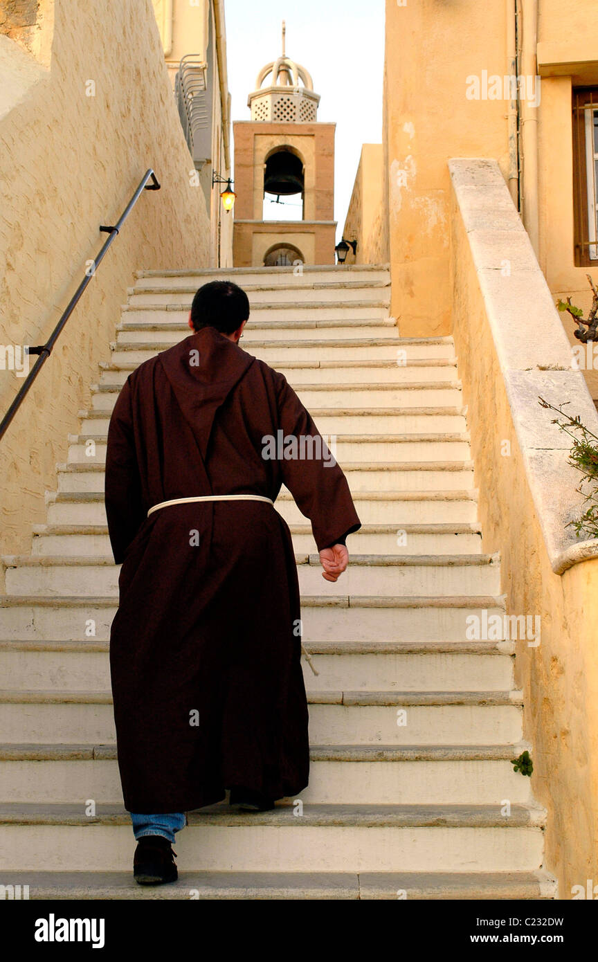 Catholic monk walking up the steps that leads to the catholic church of Saint George in Ano Syros Stock Photo