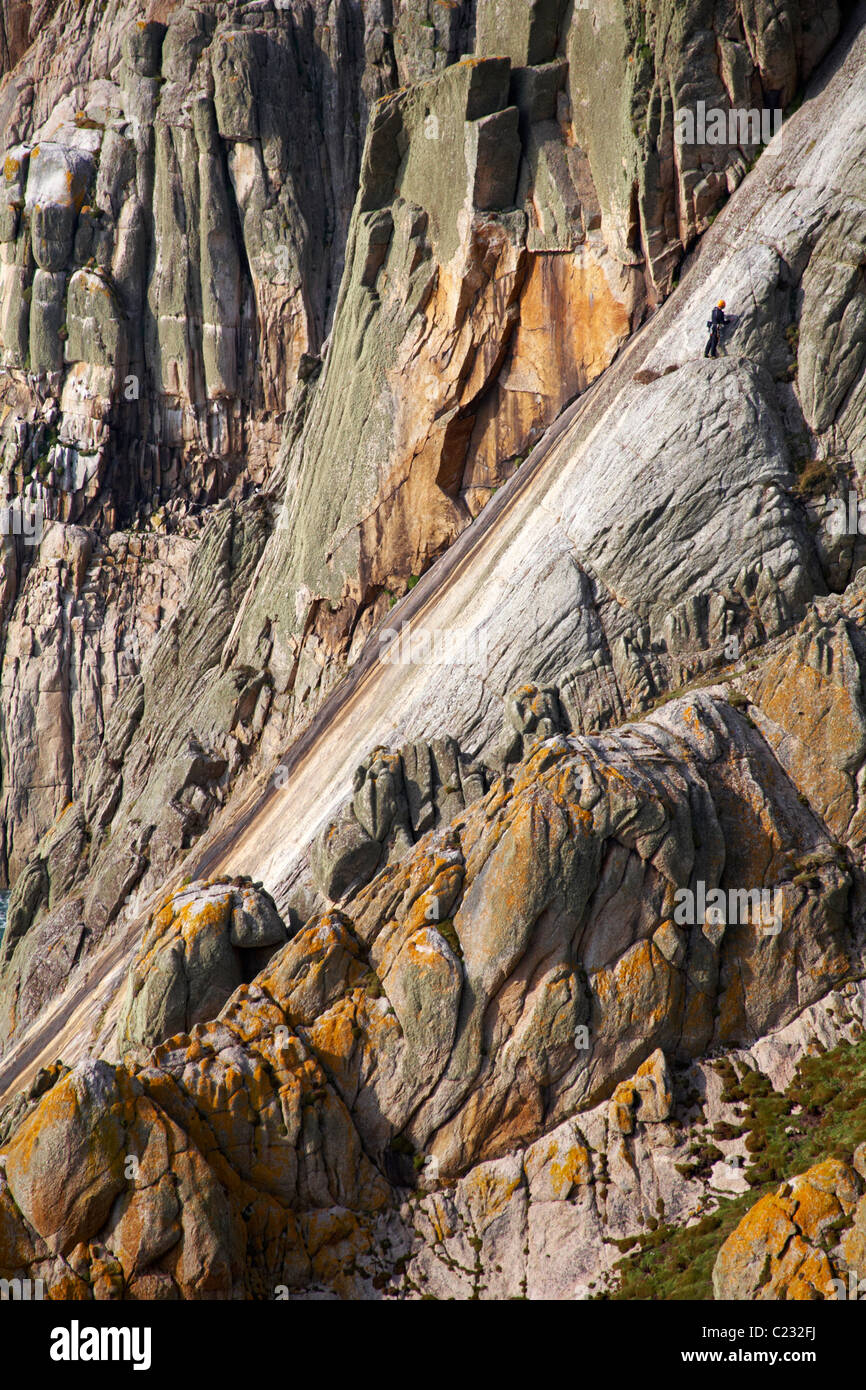 climber climbing up the Devil's Slide on the west coast of Lundy Island, Devon, England UK in March - natural plane in the granite Stock Photo