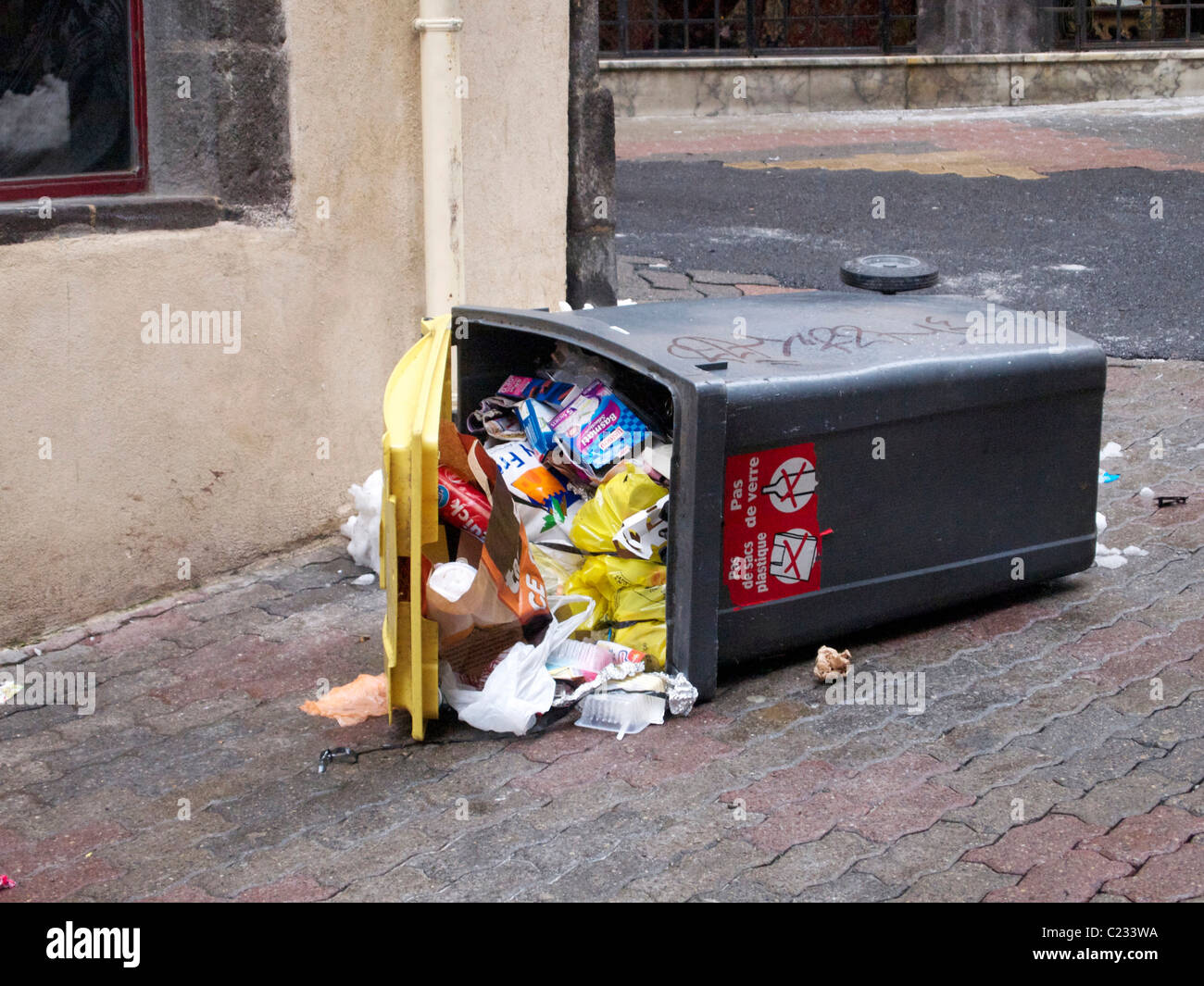 Overflowing trash bin on a city street, highlighting urban waste management issues and littering behavior. France Stock Photo