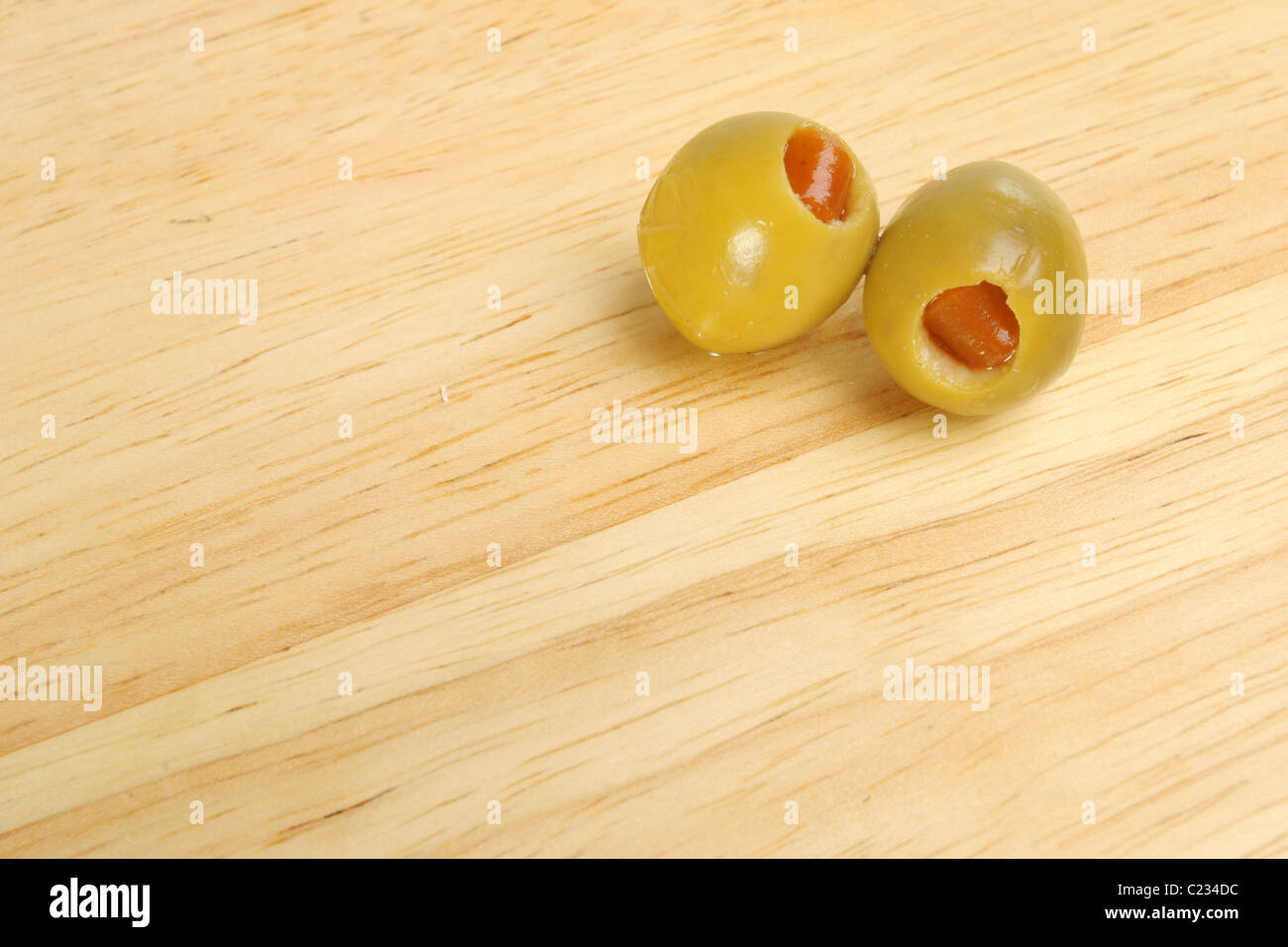 Two stuffed olives on a background of the grain of a wooden board Stock Photo