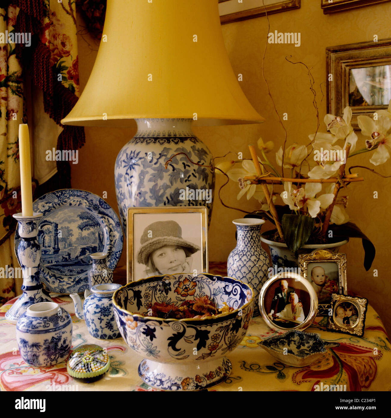 Assorted blue and white chinaware on table with yellow lampshade Stock Photo