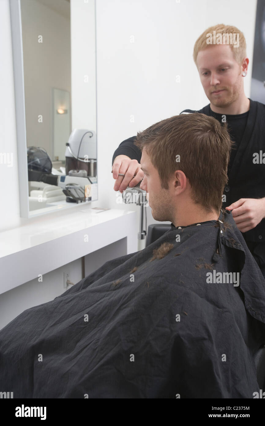 Man sitting in hairdressing robe: haircut Stock Photo