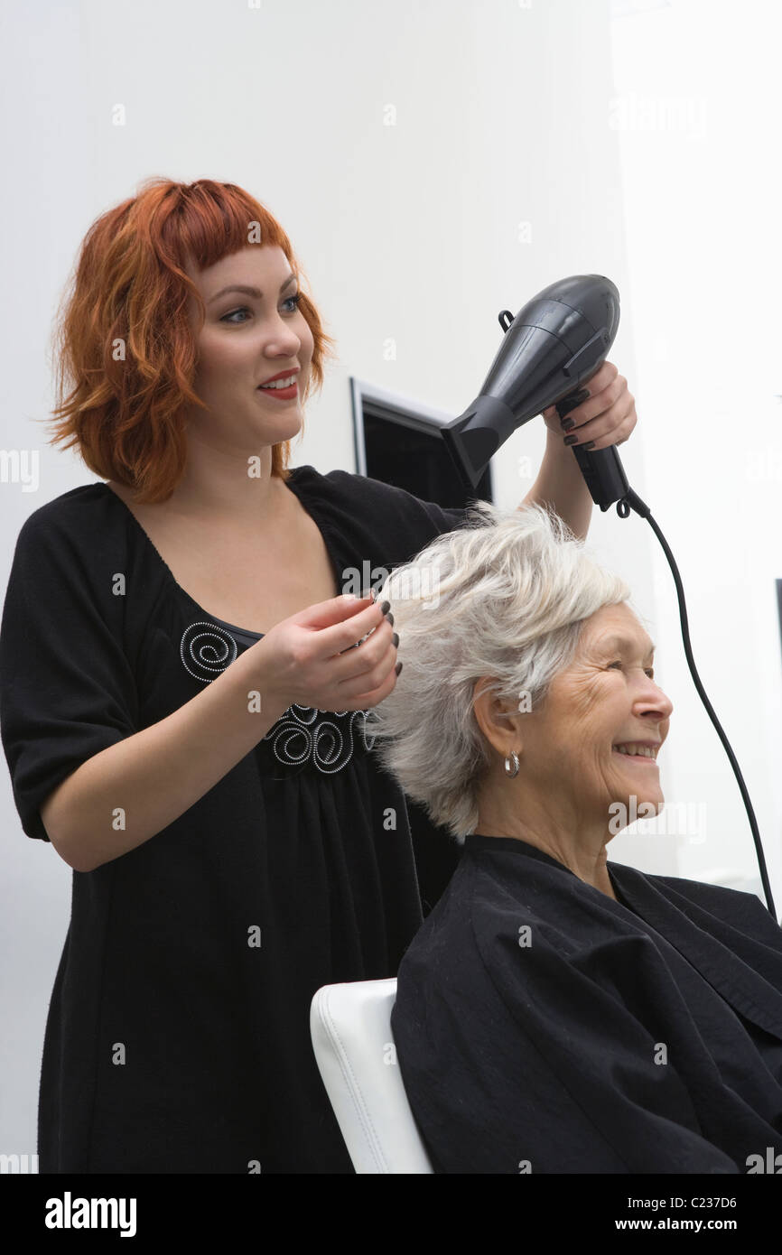 Stylist blowdrys elderly woman's hair Stock Photo Alamy