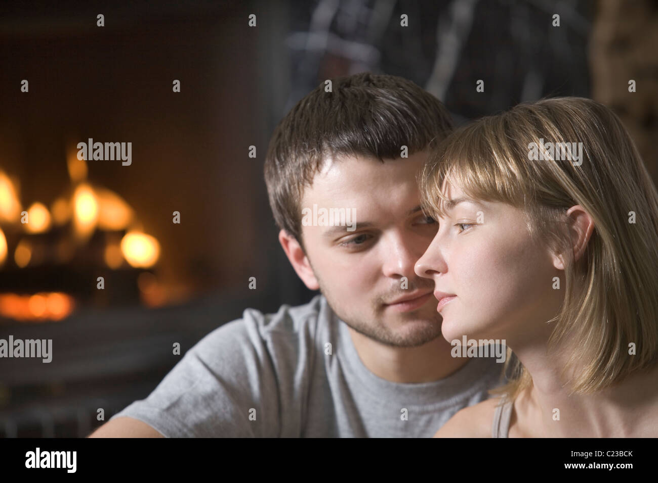 Young couple sit at open fire Stock Photo
