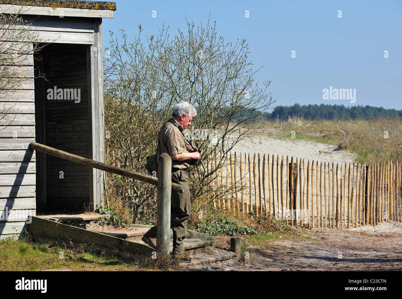 Birdwatcher with binocular leaving hide at the nature reserve Parc du Marquenterre at the Bay of the Somme, Picardy, France Stock Photo