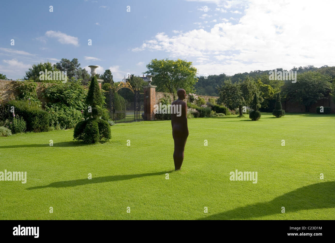 An Anthony Gormley sculpture on the lawn of a Richmond estate with topiary Stock Photo