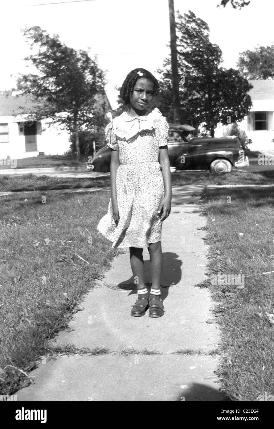 Very pretty young black girl with the family car in the background, poses outside her house in Washington suburbs, circa 1950's, U.S.A. Stock Photo