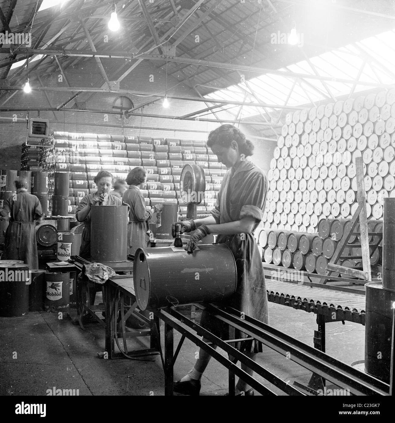 England, 1950s. Female workers put markings on fuel drums at a Mobilgas warehouse. Stock Photo