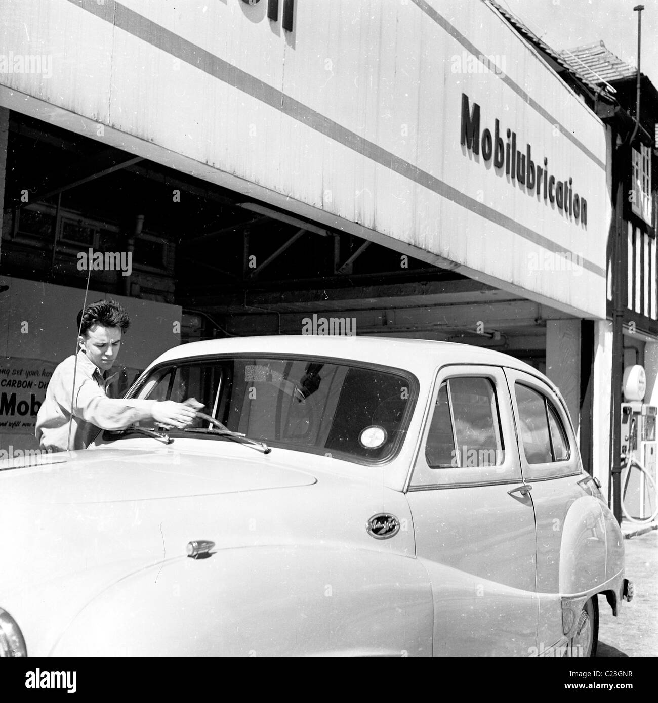 England, 1950s. Photograph by J Allan Cash of a pump attendant cleaning the front window of a car at a Mobilgas service station Stock Photo