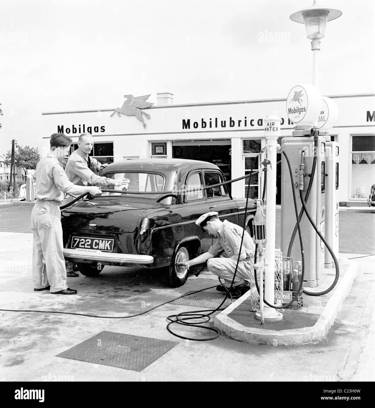 Three attendants service a car on the forecourt of the Mobilgas garage, The Whirlwind in this historical picture from the 1950s. Stock Photo