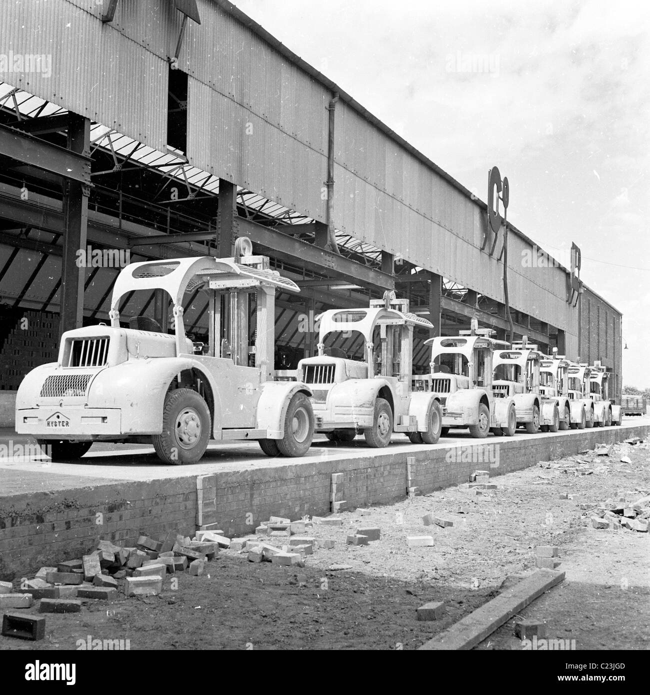 England, 1950s. A line of small fork-lift trucks outside the warehouse of the London Brick Company. Stock Photo