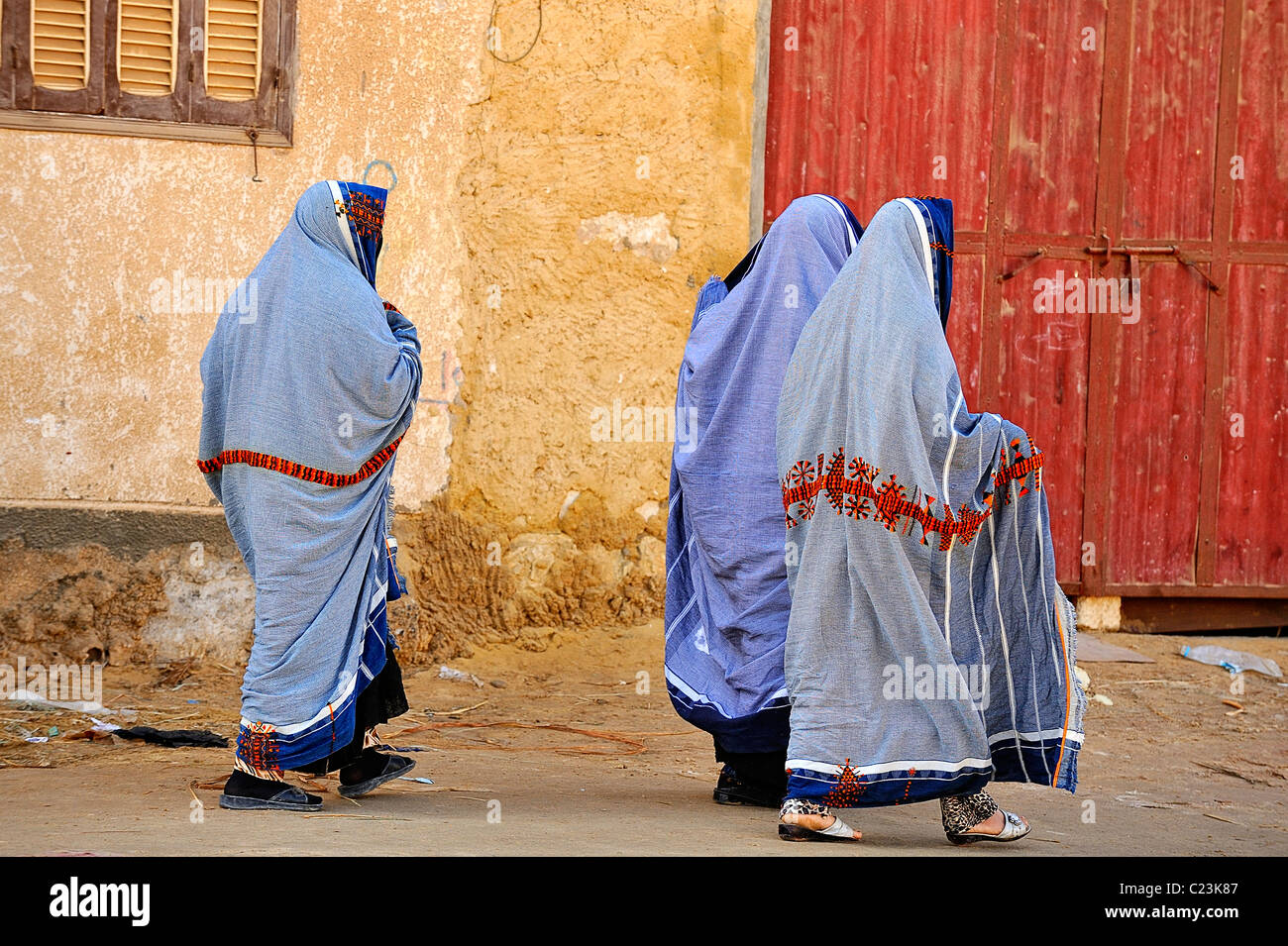 Three Egyptian women veiled wearing typical clothes and walking in a
