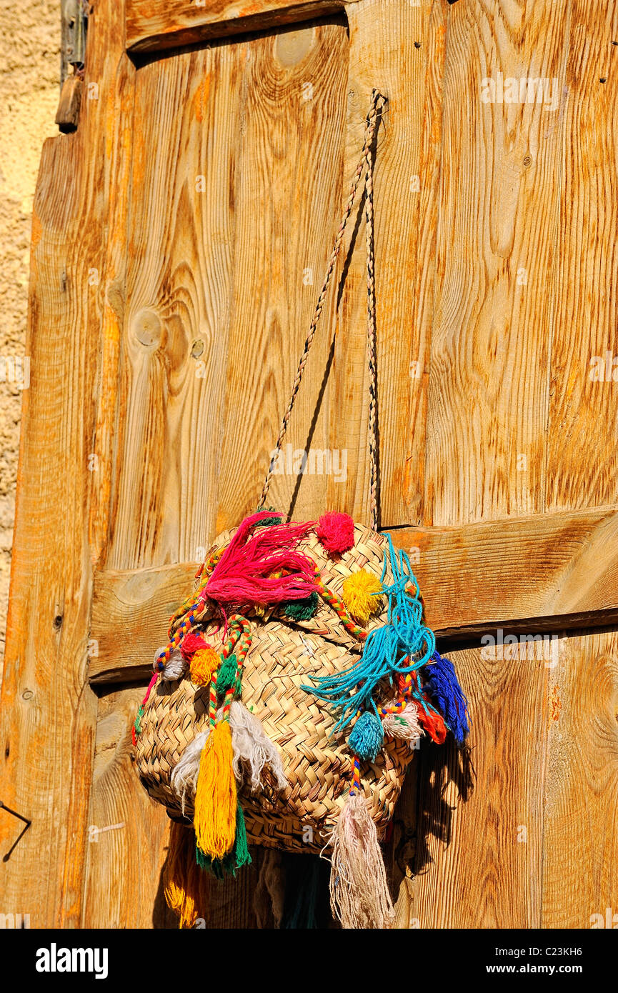 Typical Siwa basket hung on a wooden door of a house in the city of