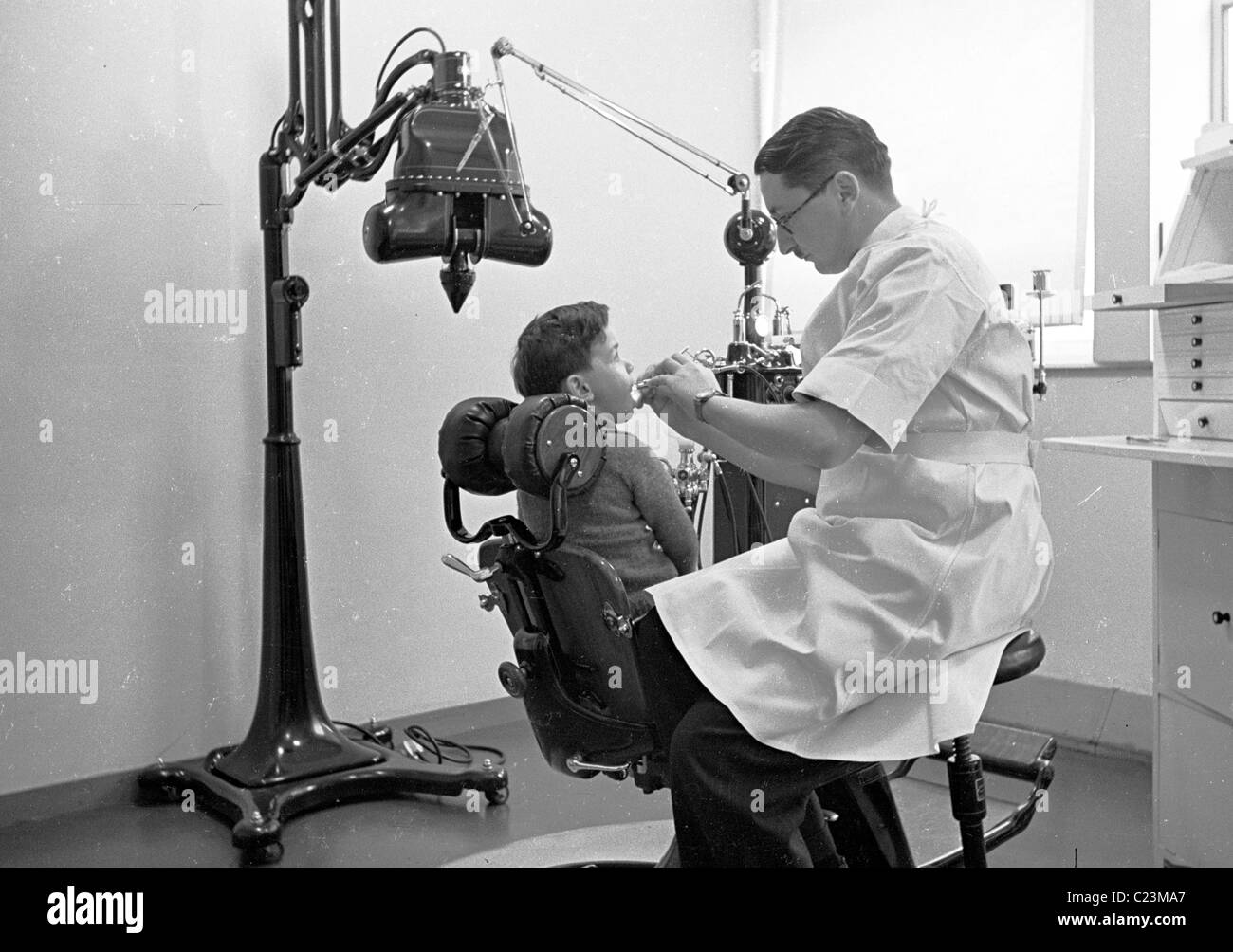 1950s. London, England. Dentist working on a child's teeth in this